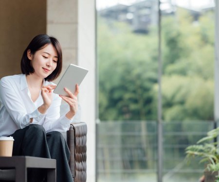 Asian businesswoman using tablet at office window